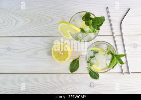 Cocktail d'été frais et rafraîchissant avec citron, menthe et glace. Deux verres de limonade ou de mojito sur fond en bois. Vue de dessus Banque D'Images