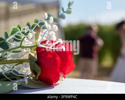 Gros plan de deux roses rouges et de fleurs de gypsophile blanches sur une table avec des figures floues en arrière-plan Banque D'Images