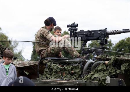 Un soldat de l'armée britannique des Light Dragoons, faisant partie du groupe de combat des forces terrestres avancées de l'OTAN-Pologne, démontre la mitrailleuse sur un véhicule Jakal lors d'une exposition statique pour la Journée des forces armées polonaises à Orzysz, en Pologne, le 16 août 2026, un jour férié national commémorant la victoire de la Pologne sur la Russie soviétique lors de la bataille de Varsovie de 1920. Banque D'Images