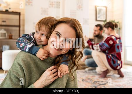 Mère heureuse recevant un câlin de son enfant à la maison Banque D'Images
