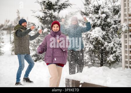 Famille heureuse ayant une bataille de boules de neige amusante en hiver Banque D'Images