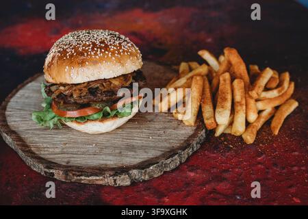 Burger gourmet au bœuf avec oignons caramélisés et frites Banque D'Images