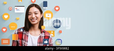 Jeune femme asiatique souriante interagissant avec des icônes de médias sociaux, concept commercial Banque D'Images