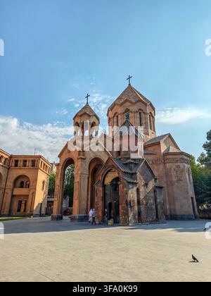 Ancienne église en pierre Sainte-Anne avec dômes et croix sous un ciel bleu clair. Des gens marchent près de l'entrée principale. Un pigeon se tient sur le sol pavé. Arbres Banque D'Images