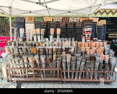 Un étal de marché en plein air présente de nombreux pinceaux disposés soigneusement sur des étagères métalliques. Les pinceaux varient en taille, type de poils et matériau de la poignée. Auvent blanc Banque D'Images