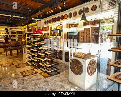 Intérieur d'une boutique d'artisanat remplie d'objets en bois et d'articles décoratifs. Les étagères exposent des sculptures complexes, des assiettes et des meubles. Le sol présente une patine Banque D'Images