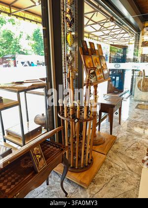 Étagère en bois antique avec des accents métalliques ornés à l'intérieur du magasin. Les étagères contiennent divers objets décoratifs près d'une fenêtre en verre. Sol en marbre et bois Banque D'Images
