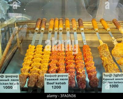Diverses viandes embrochées présentées dans une vitrine. Kebabs de bœuf à 1200. Kebabs de poulet à 1000. Morceaux de viande marinés rouges et jaunes. Laboratoire Banque D'Images