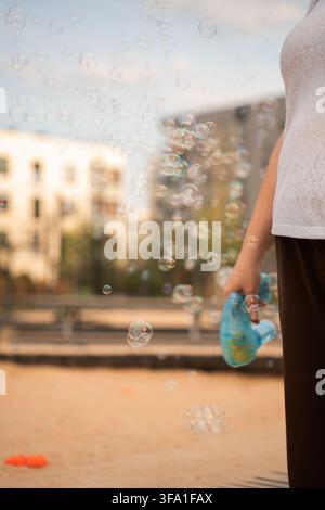 bulles de savon irisé flottant à travers une scène extérieure doucement flou, brillant sous une lumière chaude du soleil avec des réflexions pastel, un bokeh crémeux et un rêveur Banque D'Images
