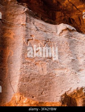Vue de pétroglyphes anciens gravés dans une paroi rocheuse de grès, représentant des figures humaines et un bouquetin dans le paysage désertique de Wadi Rum Village, Aqaba Banque D'Images
