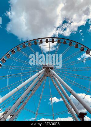 Grande roue blanche contre un ciel bleu nuageux, au Vieux-Port de Montréal, Québec, Canada. Attraction touristique par une journée d'été. Banque D'Images