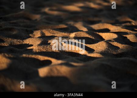 Close-up d'un sable de plage texturé ondulé sous le soleil avec lumière et ombre Banque D'Images