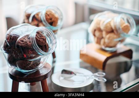 Des biscuits au chocolat noir dans un bocal et deux autres bocaux remplis de biscuits au lait sont posés sur la table lors d'une réunion professionnelle, pause thé et café Banque D'Images
