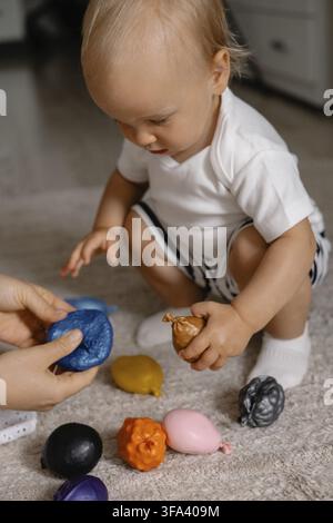 Un tout-petit se concentre intensément sur des jouets colorés, affichant de la curiosité et un engagement dans le jeu Banque D'Images