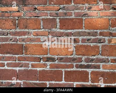 Vue détaillée d'un mur de briques rouges patiné, mettant en valeur la texture rustique et vieillie en gros plan Banque D'Images