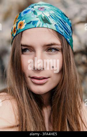 Portrait de femme portrait bandana d'une jeune femme portant un foulard floral coloré regardant sur le côté dans la nature Banque D'Images