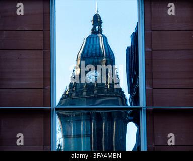 Réflexion de la tour horloge de la mairie de Leeds encadrée dans une vitre déformée d'un bâtiment moderne Banque D'Images