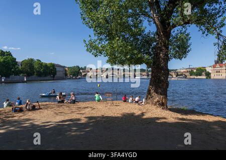 Ville de Prague en Tchéquie (République tchèque), les jeunes se détendent dans le parc de l'île de Strelecky Ostrov avec vue sur le pont Charles sur la Vltava. Banque D'Images