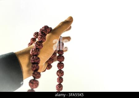 Image des perles de prière en main. Main masculine tenant rosaire, priant à dieu sur fond blanc, spiritualité religieuse. Homme tenant des perles rosaires et medi Banque D'Images