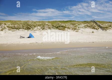 Petite tente ou abri bleu reposant sur la large plage de sable de la presqu'île de Curonie près de la mer Baltique avec des dunes couvertes d'herbe et un escalier en bois, con Banque D'Images