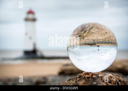 Un reflet inversé du phare de Point of Ayr capturé à l'intérieur d'une boule lenticulaire en cristal sur Talacre Beach sous un ciel nuageux au Pays de Galles du Nord. Banque D'Images