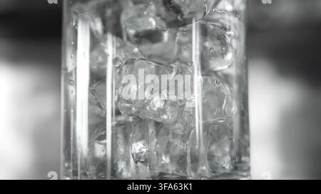 Des glaçons clairs remplissant un verre transparent, créant une boisson fraîche rafraîchissante avec des gouttes d'eau et de la condensation Banque D'Images
