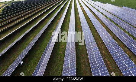 Ferme solaire générant de l'électricité propre avec des rangées interminables de panneaux photovoltaïques dans un champ vert Banque D'Images