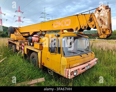 Trutnov, République tchèque - 5 août 2026 Un camion-grue CKD jaune est garé dans un champ herbeux en République tchèque. Le véhicule montre des signes d'usure, w Banque D'Images
