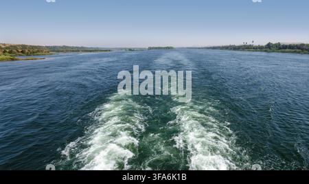 Le sillage sur le Nil formé par un croisière du Nil, laissant deux traces d'écume dans l'eau calme. Lignes de rive lointaines à gauche et à droite Banque D'Images