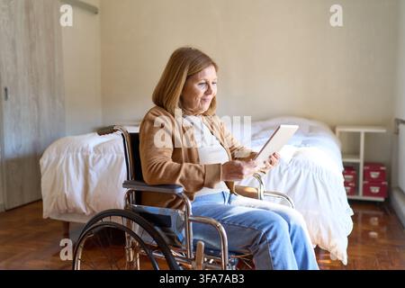 Télémédecine et soins à domicile pour les personnes âgées, femme âgée en fauteuil roulant utilisant une tablette numérique pour une consultation en ligne. Vie indépendante et digi Banque D'Images