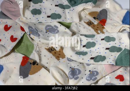 Une photographie macro détaillée capturant un arrangement superposé de chaussettes beige-blanc arborant des motifs charmants et joyeux, notamment des arbres verts Banque D'Images