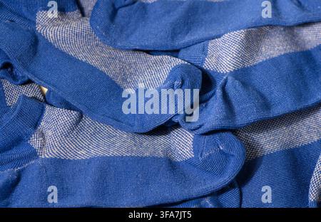 Une photographie macro détaillée affichant un tas désordonné et superposé de chaussettes à motifs bleues et blanches, mettant l'accent sur les riches tons bleus, la texture tricotée, Banque D'Images