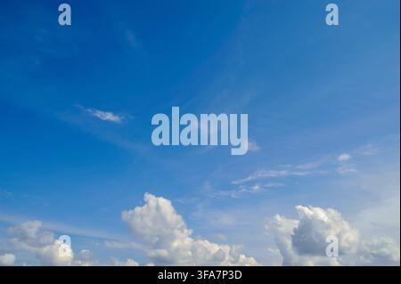 Arrière-plan de jour ensoleillé magnifique avec un ciel bleu vif et de douces nuages cumulus blancs dispersés le long de l'horizon, parfait pour la nature et la météo c Banque D'Images