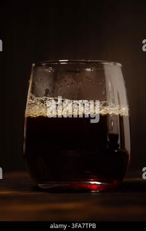 Verser du café dans un verre sur une table en bois rustique sombre Banque D'Images