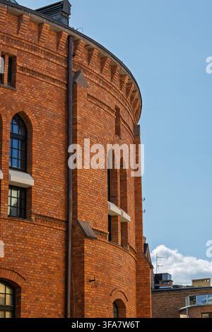 Un bâtiment rond en briques avec de hautes fenêtres en arc se dresse dans la vieille ville de Torun. Motifs décoratifs en briques et maçonnerie vieillie Banque D'Images