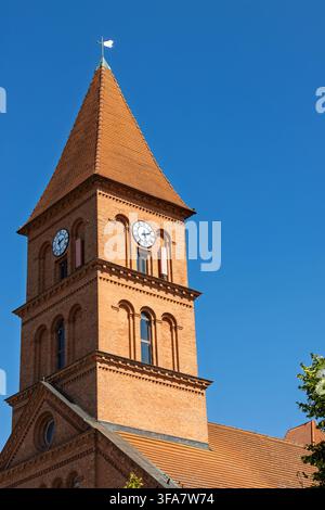 La tour d'horloge en briques de l'église de la Sainte-Trinité s'élève au-dessus de la vieille ville de Torun. Son toit pentu en tuiles, ses fenêtres en arc et sa brique décorative Banque D'Images