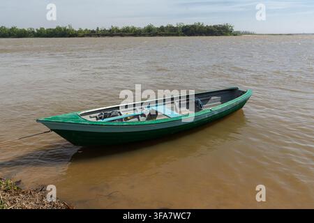 Petit bateau de pêche en bois vert ancré près de la rive de la rivière Banque D'Images