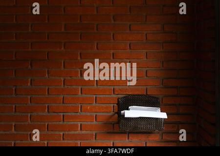 Enveloppes et lettres blanches dans une boîte aux lettres en métal fixée à un mur de briques rouges apparentes Banque D'Images