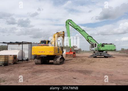 Machines industrielles lourdes et pelleteuses hydrauliques travaillant sur un chantier de construction ou dans une scierie Banque D'Images