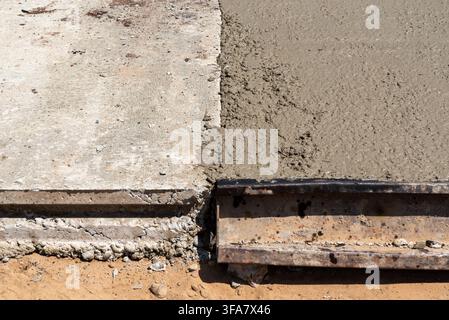 Vue rapprochée du béton frais et humide rencontrant un revêtement de béton durci à une jointure de construction Banque D'Images