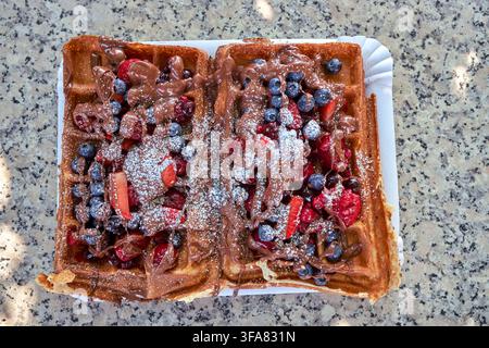 Gaufres garnies de fraises, myrtilles, framboises, chocolat et sucre en poudre Banque D'Images