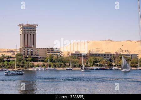 Assouan, Égypte – 10 mars 2026 : Resort Movenpick sur l'île d'Éléphantine à Assouan, avec des felouques traditionnelles et des bateaux de touristes naviguant sur le Nil, Banque D'Images