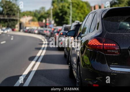 Focus arrière sur une automobile sombre dans une file de véhicules congestionnée arrêtée sur une route goudronnée pendant les heures de pointe Banque D'Images