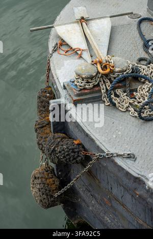 Ancre rouillée et chaîne d'amarrage sur la poupe d'un vieux bateau étroit avec pare-battage en corde sur la poupe. Banque D'Images