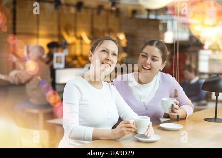 Deux amies joyeuses appréciant leur café dans un café confortable Banque D'Images
