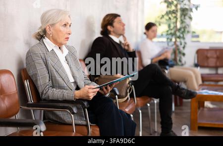 Femme d'affaires âgée concentrée attendant une réunion avec des investisseurs au bureau Banque D'Images
