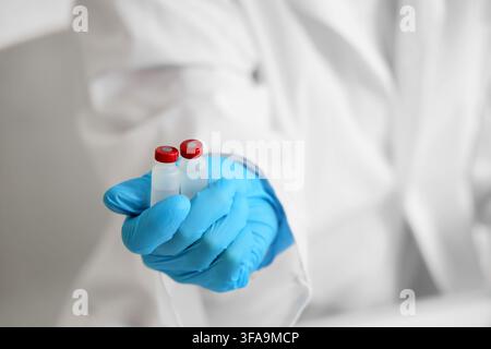 Développement de vaccins et recherche médicale, main de scientifique portant un gant bleu tenant deux flacons pour des essais cliniques Banque D'Images