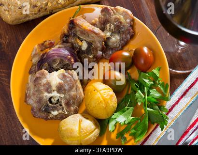 Côtelettes d'agneau avec pommes de terre cuites au four, tomates et légumes verts Banque D'Images
