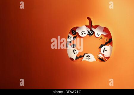 Découpage en papier de citrouille d'Halloween avec des fantômes et des chauves-souris sur fond orange Banque D'Images