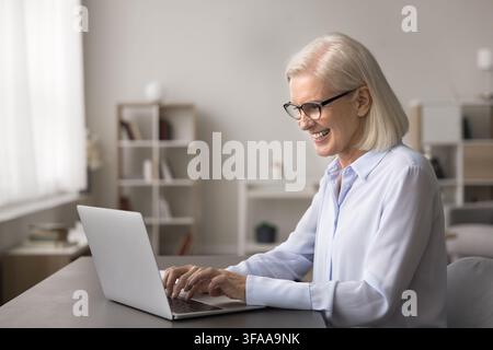 Femme d'affaires mature et réussie souriante, comptable, travaillant sur un ordinateur portable Banque D'Images